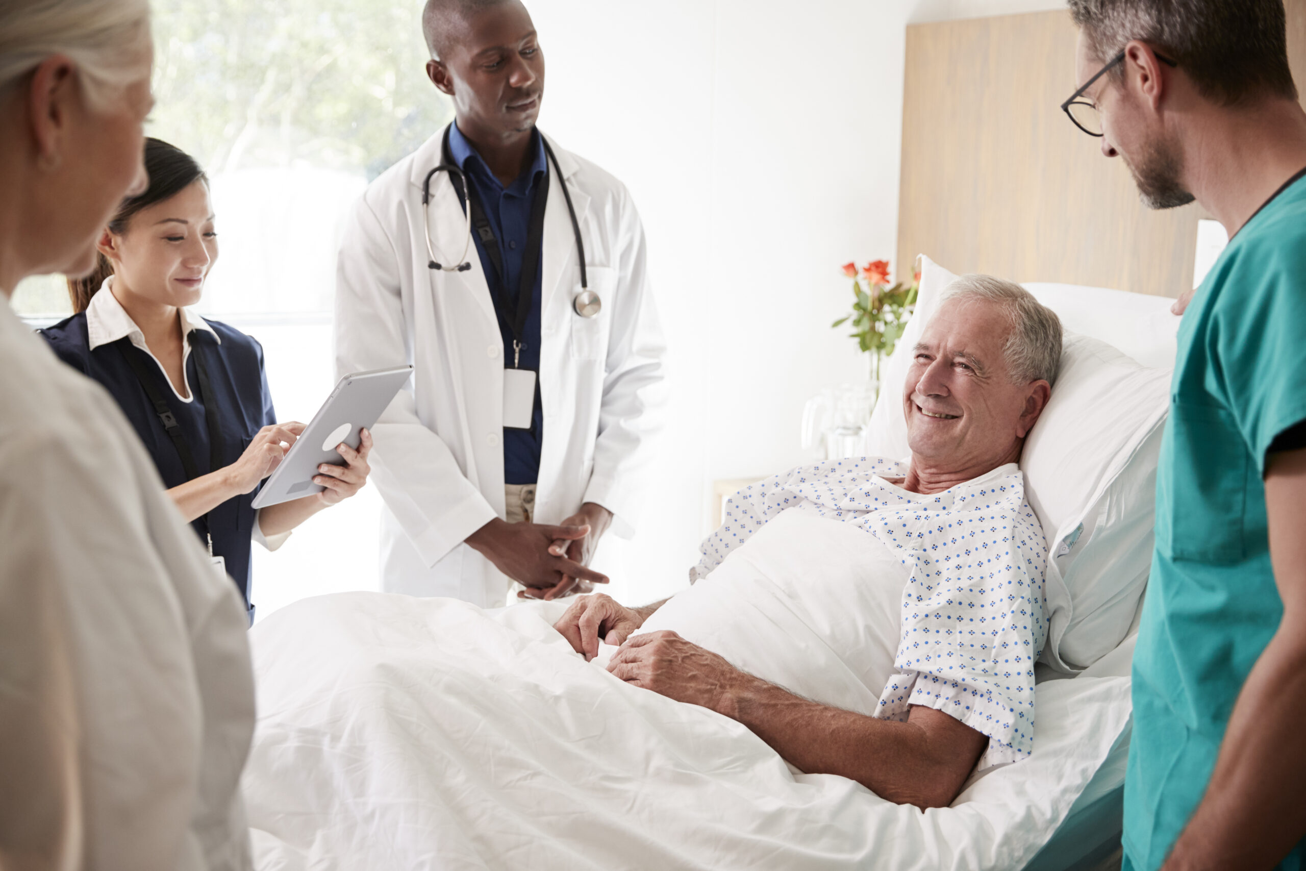 medical-team-on-rounds-meeting-around-bed-of-senio-2024-10-19-02-52-59-utc